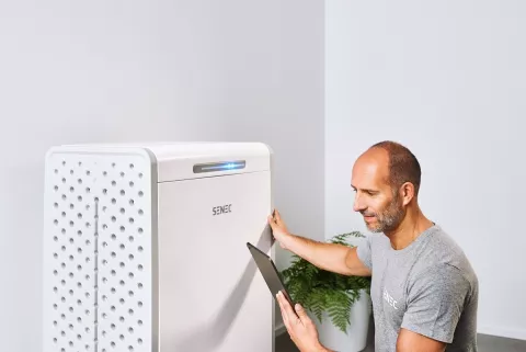 Ein Mann prüft die Leistungsdaten seines Photovoltaik-Speichers mit einem Tablet.
